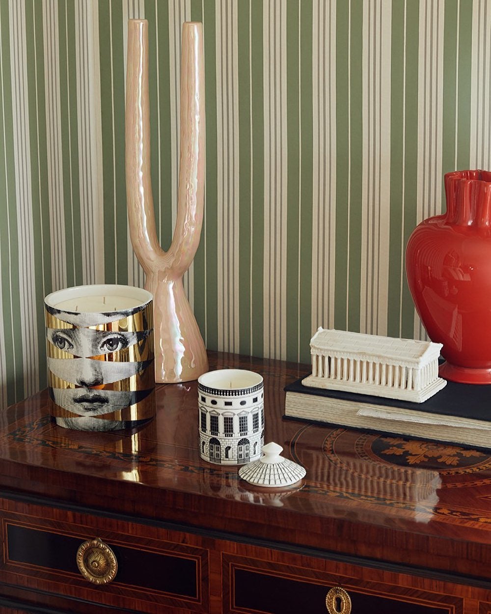 Two fornasetti candles on a a wooden dresser